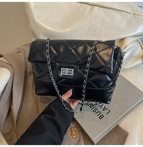 Detailed view of black quilted crossbody bag with silver chain strap and metal turn-lock