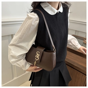 Detail of vintage brown leather underarm bag with gold S-shaped metal hardware buckle