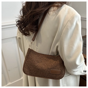 Detail of retro woven shoulder bag featuring brown twill texture and leather strap