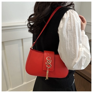 Close-up of red crescent shoulder bag featuring gold S-letter buckle and stylish tassel