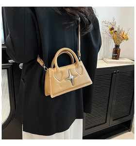 Borsa a tracolla marrone chiaro con dettaglio stella d'argento indossata da modella in tailleur