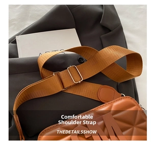 Detail of adjustable wide nylon shoulder strap and gold buckle on a brown crossbody bag