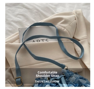 Dettaglio borsa a secchiello in denim azzurro con frange e fibbia dorata sulla tracolla