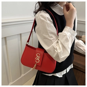 Detail of red shoulder bag with gold letter buckle and elegant tassel charm