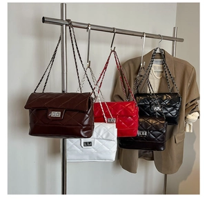 Detailed row of quilted chain bags in brown, white, red, and black on a display rack