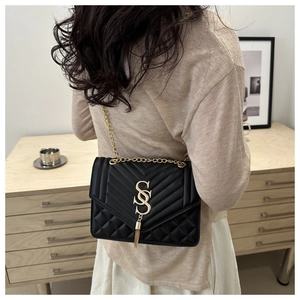 Detail of black quilted leather shoulder bag with gold hardware and chain strap