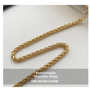 Détail macro d'une bandoulière chaîne dorée de qualité avec texture tissée et mousqueton