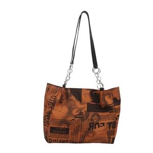 Chic orange tote bag with black newspaper print and silver chain link shoulder straps