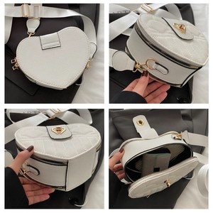 Detail view of heart-shaped white leather bag with gold heart lock and wide strap