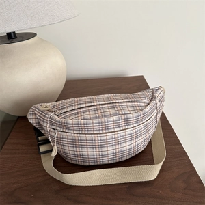 Chic plaid crossbody bag with adjustable strap and dual zipper pockets on wooden surface