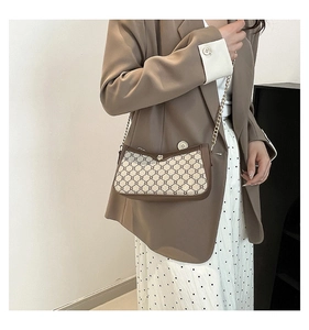 Detail of vintage beige pattern underarm bag with gold chain strap on model outfit