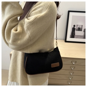 Detail of black fabric shoulder bag with brown leather piping and fashion logo patch