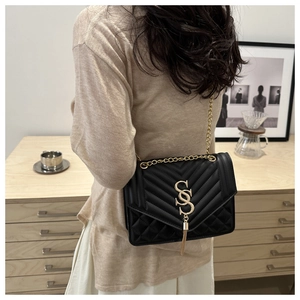 Détail du sac bandoulière noir matelassé avec logo SS doré, franges et chaîne en métal