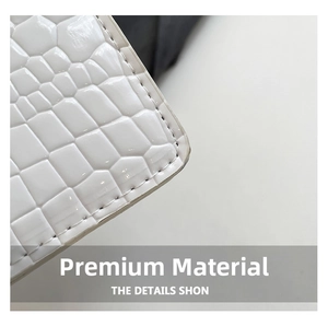 Gros plan sur la texture cuir crocodile blanc et les coutures soignées du sac à bandoulière