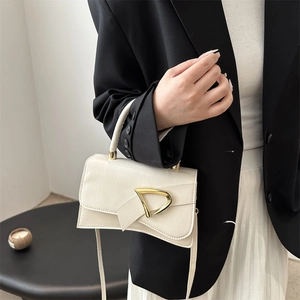 Piccola borsa quadrata beige crema con fibbia a D dorata indossata su un outfit modello