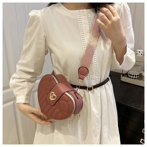 Detail of heart-shaped crossbody bag with litchi leather texture and golden heart turn-lock