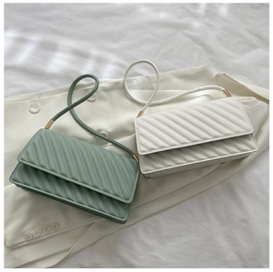 Détail de sacs bandoulière en cuir PU matelassé vert et crème avec boucles dorées