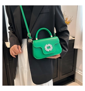 Détail du mini sac à main vert avec boucle en cristal et bandoulière métallique