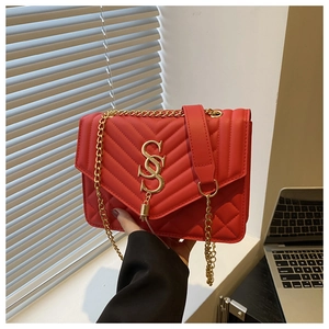 Detail of red quilted crossbody bag with golden SOS logo and metal chain strap