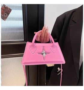 Dettaglio borsa a trapezio rosa con stella d'argento su un outfit blazer nero
