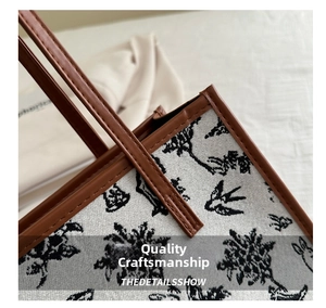 Detail of floral tapestry tote bag featuring gray jacquard fabric and brown leather handles