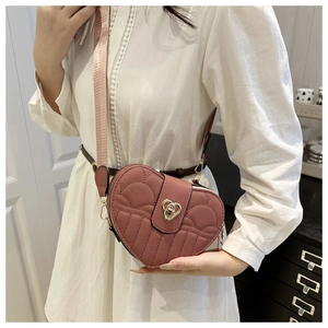 Close-up of heart-shaped crossbody bag with lychee texture and gold metal twist lock