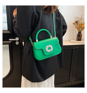 Détail d'un sac en cuir vert vif orné d'une boucle en strass étincelante et d'une bandoulière