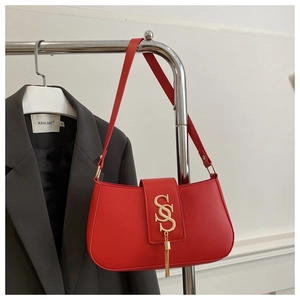 Macro shot of red leather shoulder bag featuring a vintage metal S-buckle and long tassel