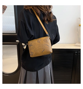 Close-up of vintage printed tote bag showing textured leather material and long shoulder strap
