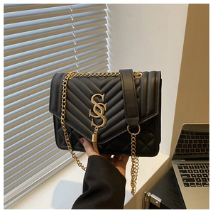 Detail of black quilted leather shoulder bag with gold logo and metal chain strap