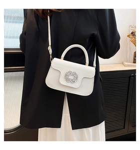 Détail d'un sac à main blanc en cuir verni avec boucle fleurie ornée de strass brillants