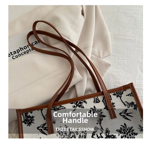 Detail of embroidered tote bag with floral silhouette and brown leather handles
