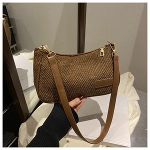 Detailed macro of brown woven baguette bag with leather strap and fashion label tag