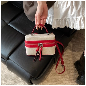 Detail of vintage canvas box bag featuring red leather trim and dual zipper closure