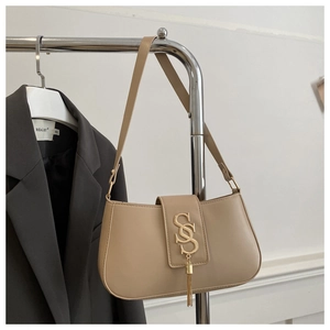 Detail of beige shoulder bag with gold S-buckle and elegant long tassel charm