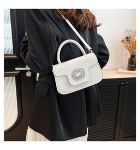 Vue détaillée d'un sac à bandoulière blanc brillant avec boucle en cristal sur le mannequin