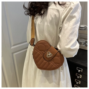 Detail of heart-shaped brown leather crossbody bag with quilted stitching and metal lock
