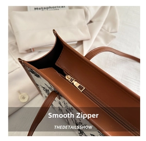 Detail of smooth gold zipper and brown leather trim on vintage canvas tote bag