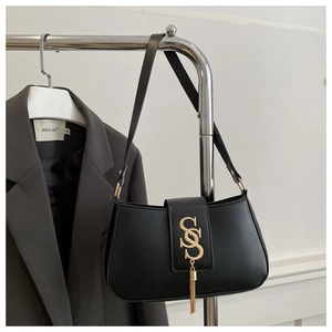Detail of black leather shoulder bag featuring gold S logo and chain tassel accents