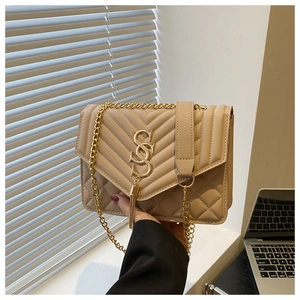 Detail of beige quilted shoulder bag with gold tassel, metal logo and chain strap