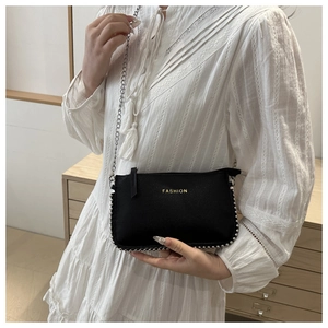 Detail of black crossbody bag with silver bead edges and metallic chain strap
