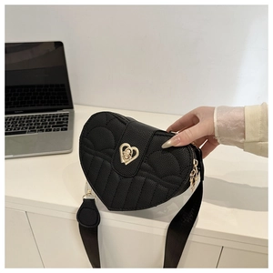 Detail of black heart-shaped quilted leather bag with golden twist lock and wide strap