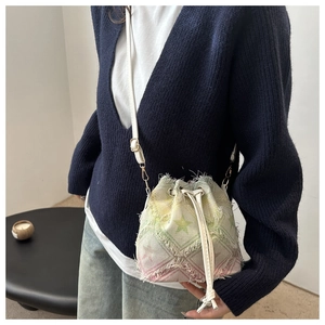Detail of mini drawstring bucket bag with pastel star patterns and frayed edges on shoulder