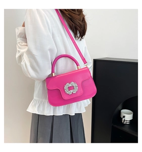 Detail of rose pink handbag featuring a round crystal buckle and smooth leather texture