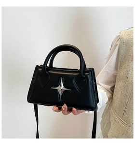 Dettaglio di una borsa in pelle nera opaca con decorazione a stella argentata a quattro punte