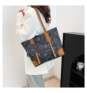 Macro detail of the letter print tote bag with brown leather handles and brand logo