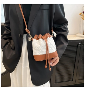 Close-up of quilted bucket bag with contrast trim and gold-tone drawstring hardware