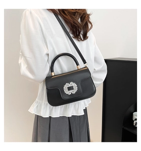 Détail d'un sac à main noir plissé avec boucle en cristal et poignée supérieure