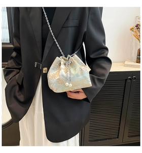 Détail du sac seau en satin bleu clair avec broderie dorée et cordon en perles