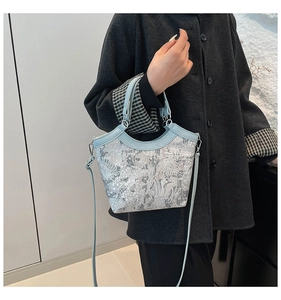 Detail of floral jacquard handbag featuring light blue leather straps worn with black coat